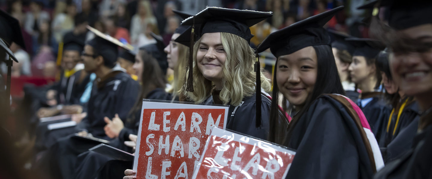 Two students wearing caps and gowns at the 2023 Commencement ceremony