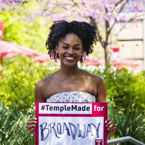Jasmine Villaroel holding a Temple Made for sign outside on Main Campus