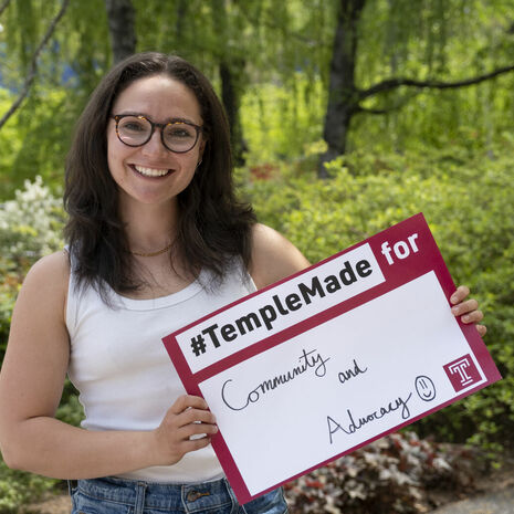 Trista Mayo standing outside holding up a Temple Made for sign