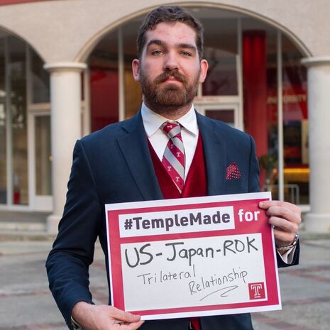 Soren holds sign saying “#TempleMade for US-Japan-ROK Trilateral Relationship” 