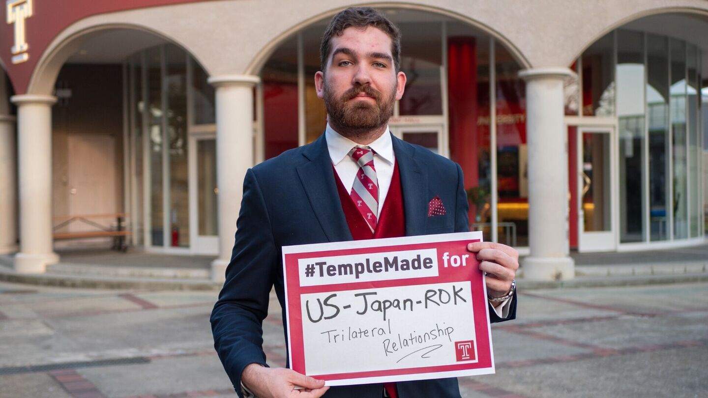 Soren holds sign saying “#TempleMade for US-Japan-ROK Trilateral Relationship” 